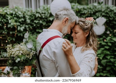 Mature bride and groom having a romantic moment at wedding reception outside in the backyard. - Powered by Shutterstock