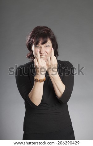 Mature brunette woman making faces against gray background