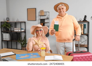 Mature business people with passport and starfish ready for summer vacation in office - Powered by Shutterstock