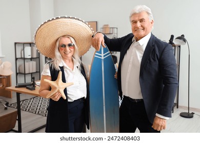 Mature business people with starfish and surfboard ready for summer vacation in office - Powered by Shutterstock
