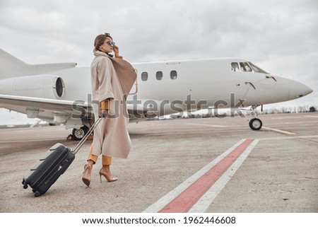 Mature business woman in coat near her jet in airport