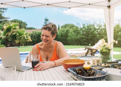 Mature Business Woman Enjoying Her Holiday By The Pool At Home, Making A Video Call On Her Laptop. Summer Holiday Person Sunbathing In The Garden. Concept Summer And Free Time.