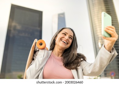 Mature Business Woman Is Happy With Her Smartphone And A Skateboard In The City