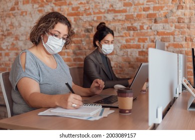 Mature Business Woman Taking Notes And Writing In Paper At Desk 