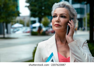 Mature Business Woman Using Smartphone In The City Street. Copy Space