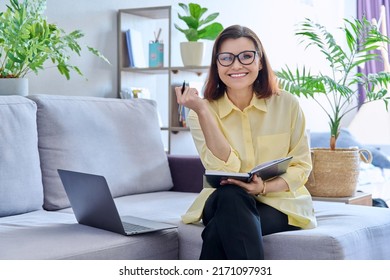 Mature Business Woman Working On Couch, Using Laptop Looking At Camera