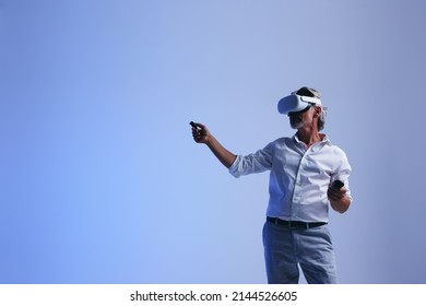 Mature Businessman Doing A Presentation In The Metaverse. Senior Businessman Leading A Virtual Meeting With His Team. Businessman Working With His Colleagues Using Virtual Reality Technology.