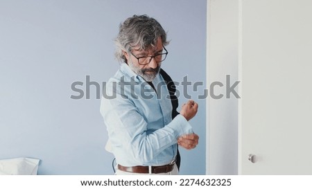 Mature businessman getting dressed in the bedroom in the morning