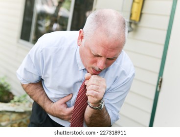 Mature businessman with gray hair, doubled over with a bad cough from a cold, flu, or ebola  - Shutterstock ID 227318911