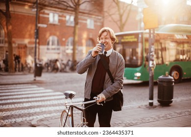 Mature businessman having a cup of coffee in the morning while commuting to work with a bicycle - Powered by Shutterstock