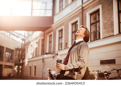 Mature businessman having a cup of coffee in the morning while commuting to work with a bicycle - Powered by Shutterstock