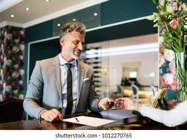 Mature businessman at hotel reception. - Powered by Shutterstock