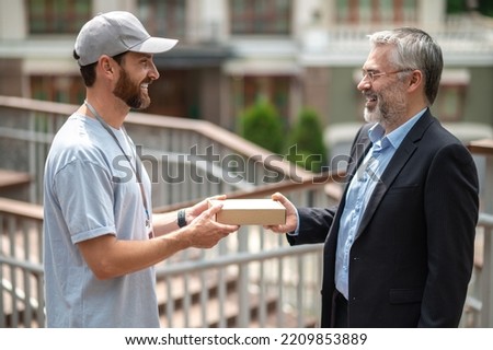 Mature businessman meeting the courrier from the delivery service