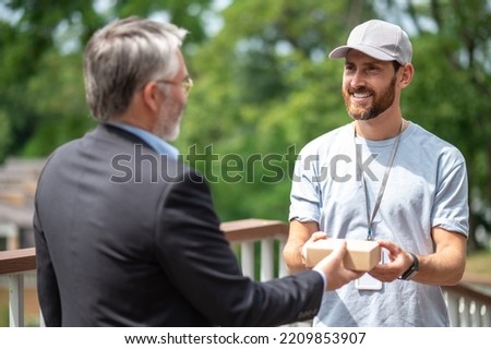 Mature businessman meeting the courrier from the delivery service