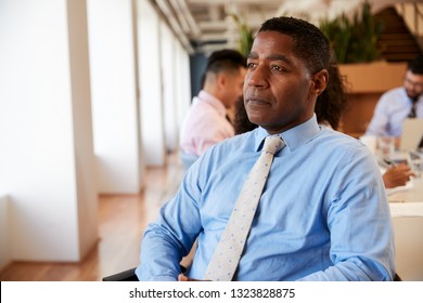 Mature Businessman In Modern Office With Colleagues Meeting Around Table In Background