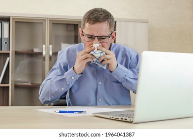 Mature Businessman At Office Desk Blowing His Nose. A Cold Office Worker Blows His Nose Into A Handkerchief. Cold And Sickness In The Workplace. Allergy