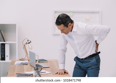 mature businessman with painful backache at office