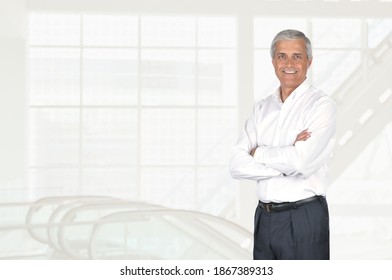 Mature Businessman Portrait With His Arms Folded, In High Key Modern Office Setting. 