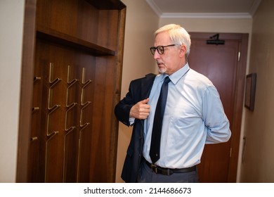 Mature Businessman Putting His Suit On A Coat Rack