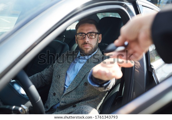 Mature businessman\
renting the car for business trip he getting keys from manager\
while sitting in car\
salon