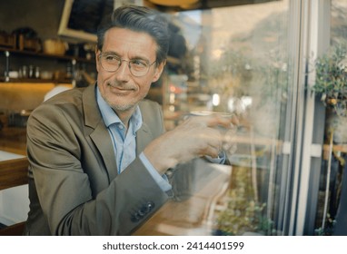 Mature businessman sitting in coffee shop- drinking coffee - Powered by Shutterstock