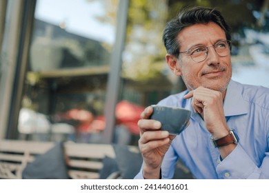 Mature businessman sitting in coffee shop- drinking coffee - Powered by Shutterstock