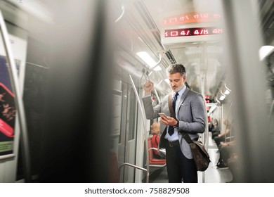 Mature businessman with smartphone in a metro train. - Powered by Shutterstock