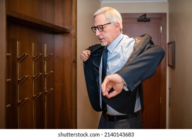 Mature Businessman Taking His Suit From A Coat Rack