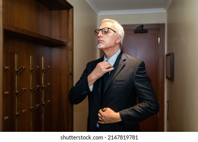 Mature Businessman Taking His Suit From A Coat Rack