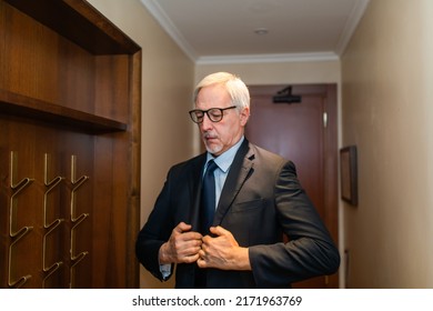 Mature Businessman Taking His Suit From A Coat Rack