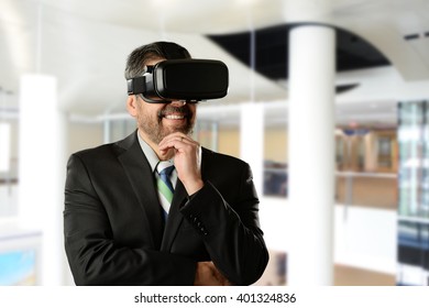 Mature Businessman Wearing Virtual Reality Goggles Inside An Office Building