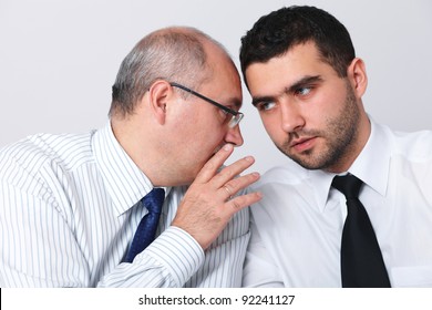 Mature businessman whisper something to his younger colleague, privacy, secret concept