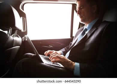 Mature Businessman Working With Notebook While Sitting Inside An Airplane