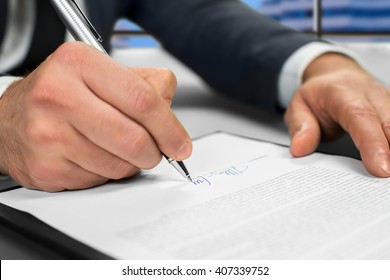 Mature businessman's hand signing document. Man signs paper beside window. New insurance policy. Official letter to a partner.