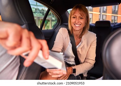 Mature Businesswoman In Back Of Taxi Paying Fare Using Contactless Payment App On Mobile Phone - Shutterstock ID 2109051953