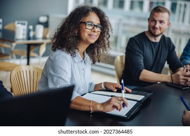 Mature businesswoman with a file sitting in meeting with her team. Female entrepreneur having meeting with colleagues in boardroom. - Shutterstock ID 2027364485