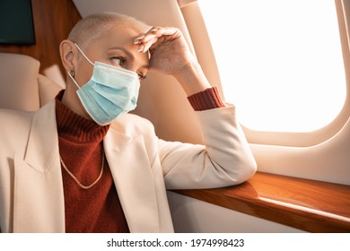 Mature Businesswoman In Medical Mask Looking At Window In Private Plane
