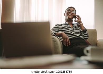 Mature Businesswoman Sitting On Couch And Talking On Phone In Hotel Room. Woman In Formal Clothes Relaxing In Hotel Room And Making Phone Call.