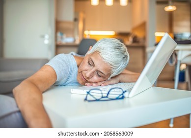 Mature Businesswoman Sleeping At Workplace. Shot Of A Mature Businesswoman Falling Asleep At Her Desk While Working In An Home Office At Night. Menopausal Mature Woman At Work Feels Bad