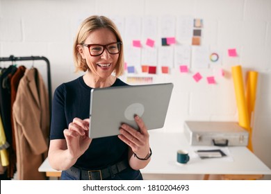 Mature Businesswoman Using Tablet Computer In Studio Of Start Up Fashion Business