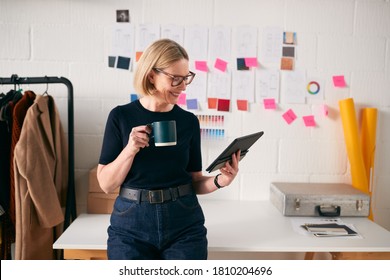 Mature Businesswoman Using Tablet Computer In Studio Of Start Up Fashion Business