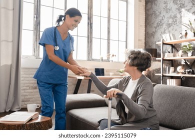Mature caregiver nurse medical worker helping old elderly senior patient grandmother to stand walk. Geriatrics concept. Disability in motion, immobility, handicapped patient - Shutterstock ID 2395115079