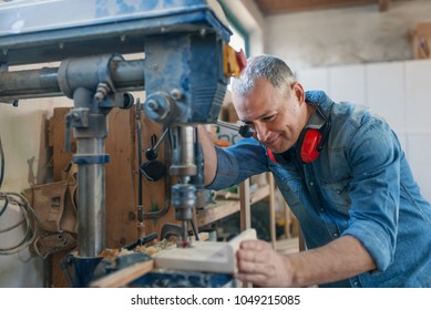 Mature Carpenter Using Drill Press In Workshop. Wood Working. Carpentry Workshop Routine. Engineer In Workshop