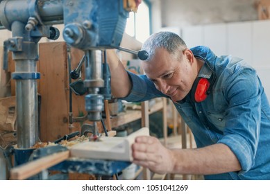 Mature Carpenter Using Drill Press In Workshop. Wood Working. Carpentry Workshop Routine. Engineer In Workshop