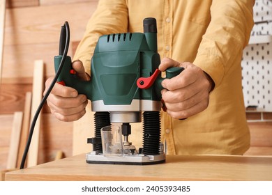 Mature carpenter working with milling machine at table in shop, closeup - Powered by Shutterstock