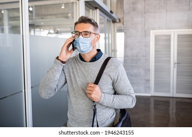 Mature casual businessman talking over phone while wearing surgical face mask during covid pandemic. Successful business man wearing face mask protecting himself from coronavirus in office. - Powered by Shutterstock