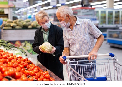 reife kaukasische Paare in Maske und Handschuhe mit covid-Schutz picks Tomaten im pflanzlichen Teil des Supermarkts