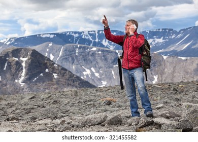 Mature Caucasian Hiker A Man Shows To The Mountain Top, Talking On A Cell Phone