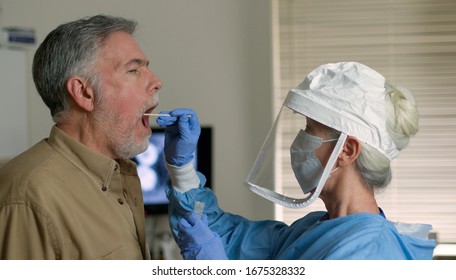 A mature Caucasian man in a clinical setting being swabbed by a healthcare worker in protective garb to determine if he has contracted the coronavirus or COVID-19.