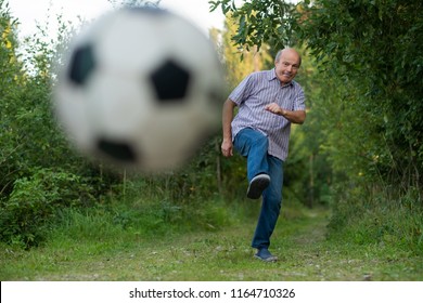 Mature Caucasian Man Kicking A Soccer Ball Outdoor. Ball Is Blurred.